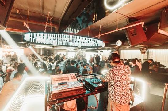 DJ playing under a piano-key patterned light fixture at a Lucknow club