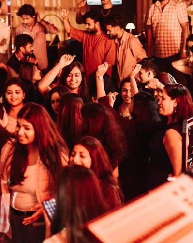 Group of women dancing on the floor with DJ equipment in the foreground at a Lucknow venue