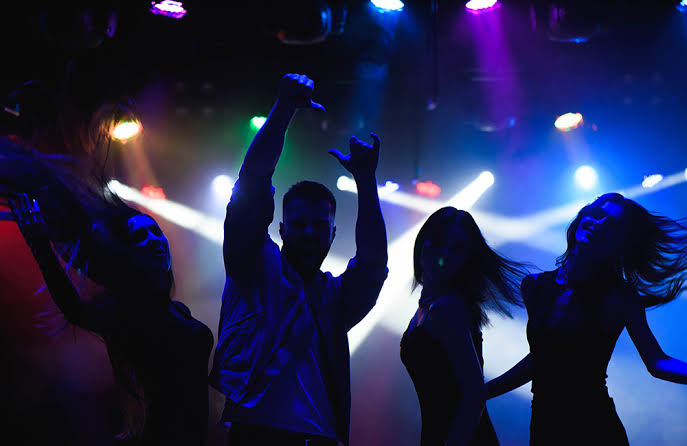 Silhouettes of guests dancing under colorful stage lights at a Lucknow night