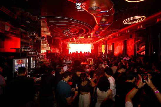 Packed dance floor under red neon rings at a Mumbai club