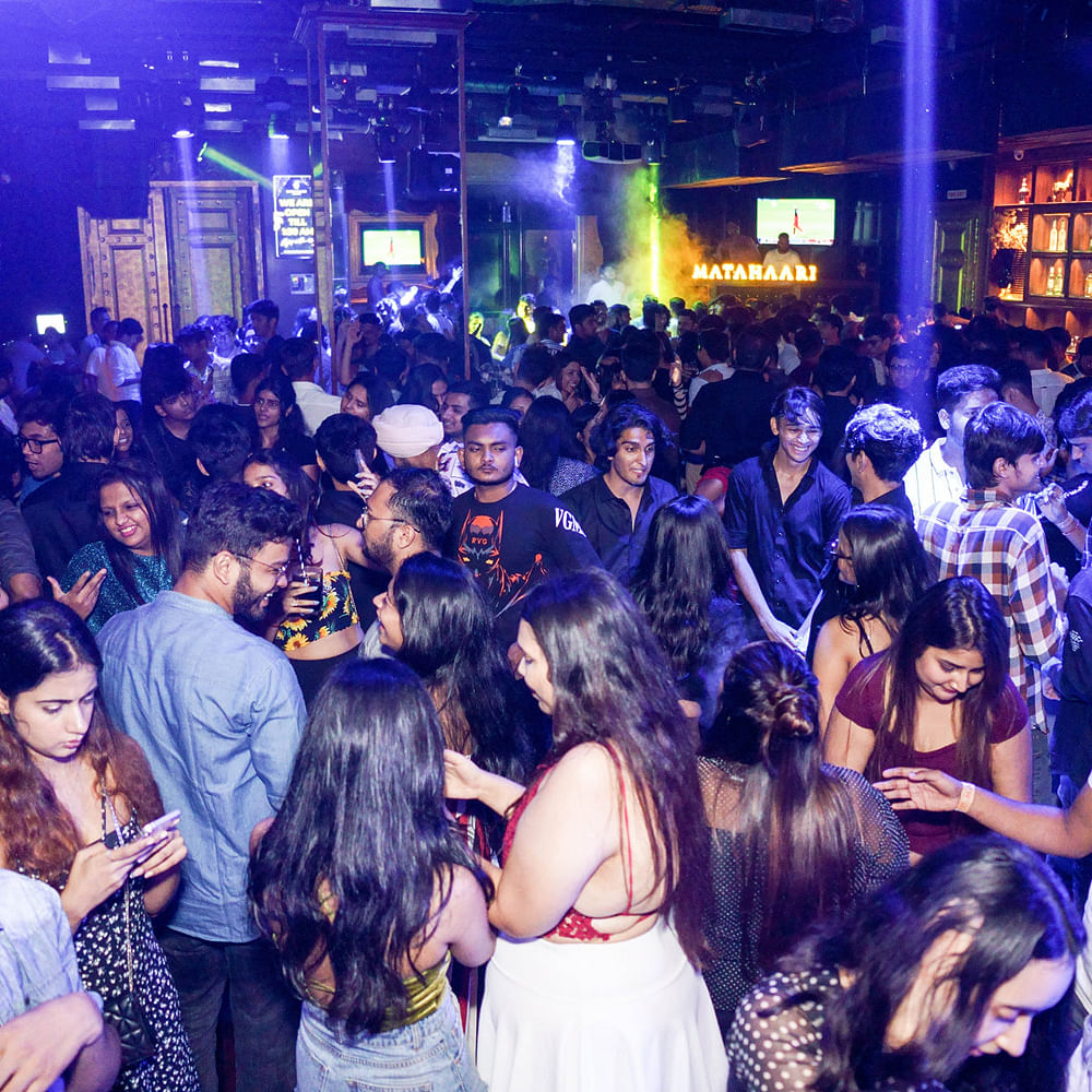 Crowd mingling under blue and purple lights at a Pune venue