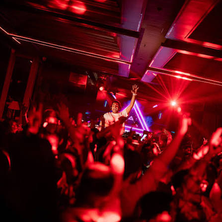 Crowd raising hands under red laser beams at a Pune club