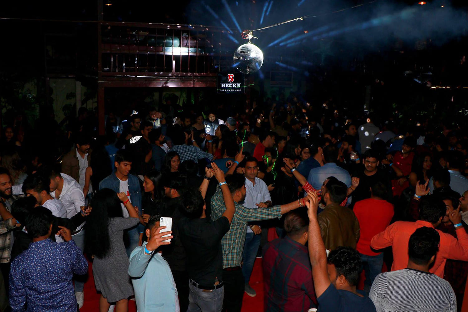 Large crowd dancing under a disco ball at a Pune night event